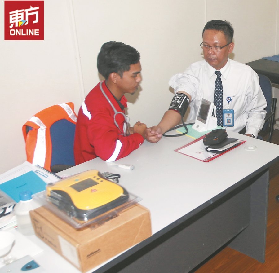 末查哈莫（右）巡视集中式员工宿舍的诊所时，也顺道检视自己的血压，体验诊所医护人员的技术。